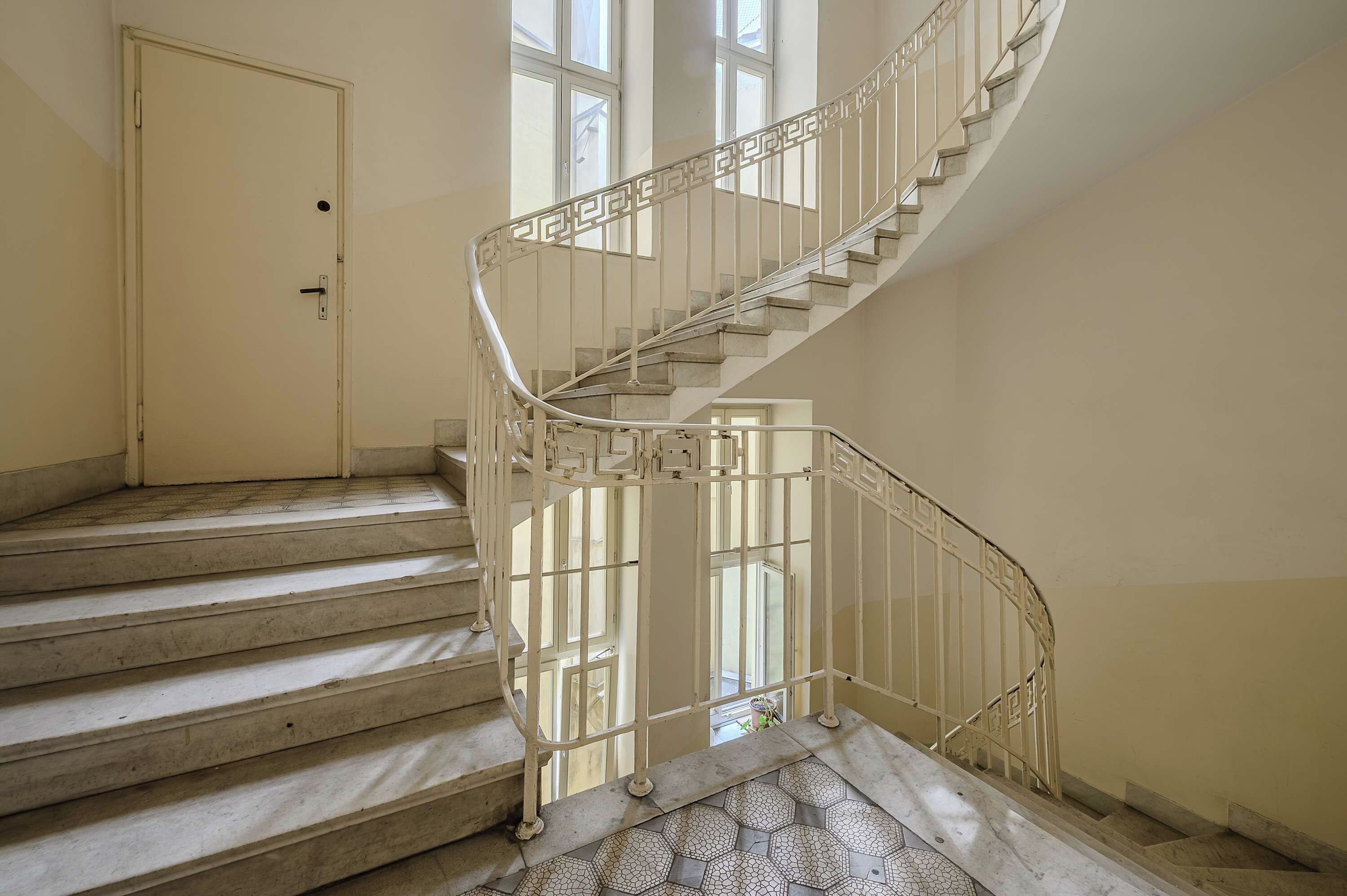 A spiral staircase with a metal railing, leading to an upper floor.