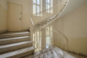 A spiral staircase with a metal railing, leading to an upper floor.
