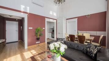 A living room with a sofa, a glass coffee table, and a dining area with chairs and a table.