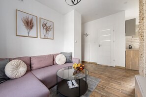 A modern living room with a sofa, a coffee table, and two framed pictures on the wall. - Lumina Family 4-room Apart near Metro & Center (Warszawa)