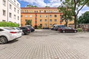 Ein Parkplatz mit mehreren Autos und einem Gebäude mit rotem Dach im Hintergrund.