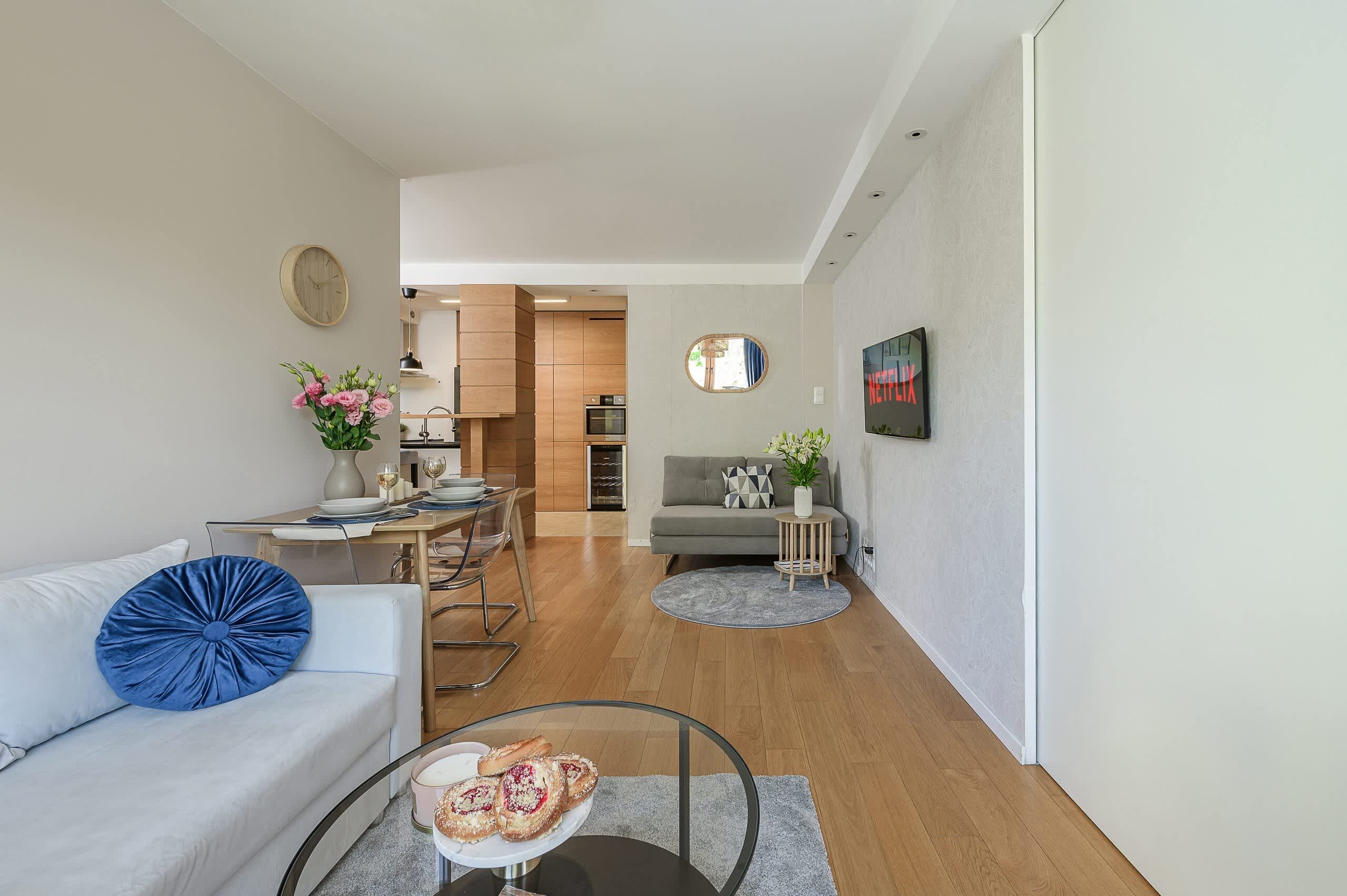 A modern living room with a sofa, coffee table, and a dining area with a table set for two.