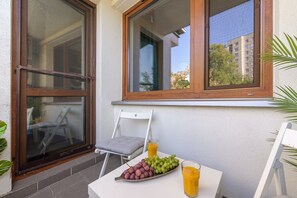 A balcony with a table, a chair, a window, and a plant. - Lumina Premium 3-room Apart w/ Parking & Balcony (Warszawa)