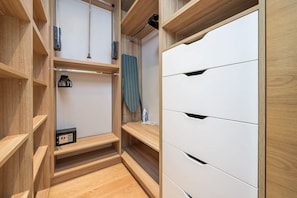 A walk-in closet with wooden shelving, a hanging rack, and a white storage unit with drawers. - Lumina Premium 3-room Apart w/ Parking & Balcony (Warszawa)