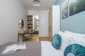 Een slaapkamer met een bed, bureau, stoel, kledingkast en een boekenkast.