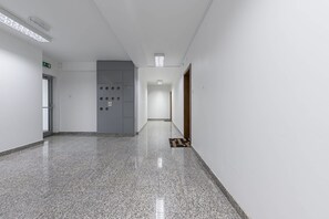 A hallway with a polished floor, a fire alarm, and a door with a handle. - Lumina Premium 3-room Apart w/ Parking & Balcony (Warszawa)