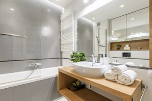 Een moderne badkamer met een bad, een wastafel en een spiegel.