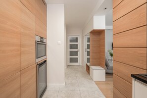Cocina moderna con armarios de madera, electrodomésticos de acero inoxidable y suelo de baldosas.