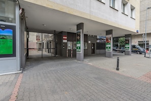 A building entrance with a gated driveway, a sign prohibiting parking, and a pedestrian pathway.