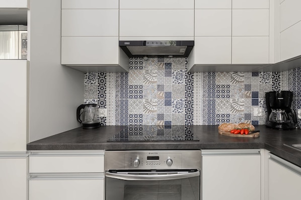 A modern kitchen with a black countertop, a coffee maker, a kettle, and a toaster.