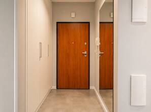 A hallway with a wooden door, a light switch, and a thermostat on the wall. - Lumina 3-room Apart w/ Parking & AC & Balcony (Warszawa)