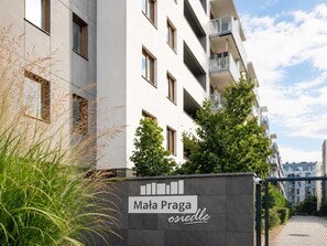 A modern apartment building with a sign reading 'Mala Praha osiedle'. - Lumina 3-room Apart w/ Parking & AC & Balcony (Warszawa)