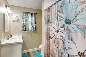 Ein Badezimmer mit weißem Waschbecken, Toilette und einer Duschvorhang mit Blumenmuster.