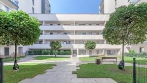 A modern building with a central courtyard, surrounded by greenery and a paved walkway. - Lumina 2BR Apart w/ Parking I Center I Balcony (Łódź)