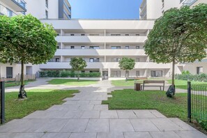 Ein modernes Gebäude mit einem zentralen Innenhof, umgeben von Grünflächen und einem gepflasterten Weg.