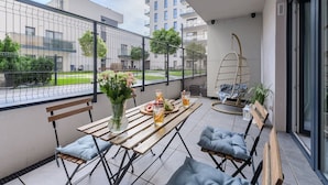 A balcony with a wooden table, chairs, a hanging chair, and a potted plant. - Lumina 2BR Apart w/ Parking I Center I Balcony (Łódź)