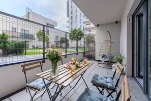 Ein Balkon mit Holztisch, Stühlen, einer Hängematte und einem Blumentopf.