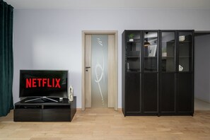 A room with a black cabinet, a door with a decorative glass panel, and a television displaying 'NETFLIX'. - Lumina 2-room Apart w/ Balcony & near Metro & Warsaw (Warszawa)