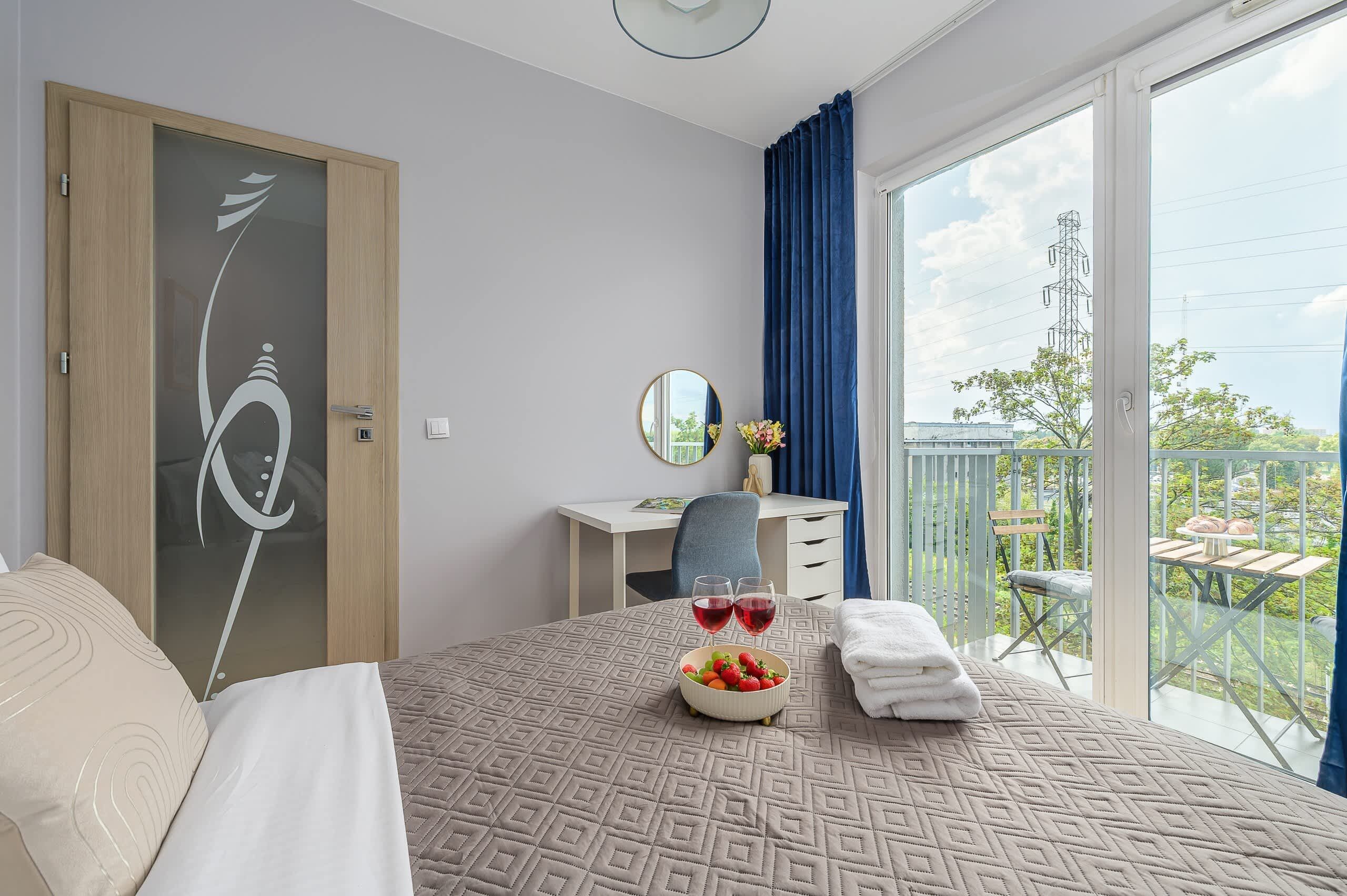 Ein Hotelzimmer mit Bett, Schreibtisch, Stuhl, einem Balkon mit Tisch und Stühlen sowie Blick ins Freie.