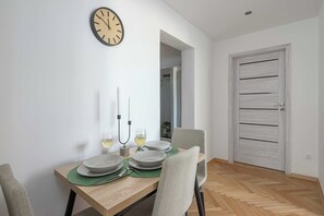 En matplats med ett träbord dukat för två personer, två ljus och två glas vitt vin.