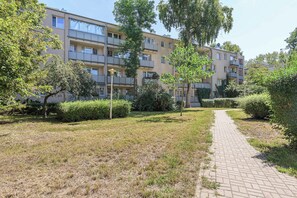 A residential building with multiple balconies, a paved pathway, and surrounding greenery. - Lumina 3-room Apart w/ Balcony near Park & Metro (Warszawa)