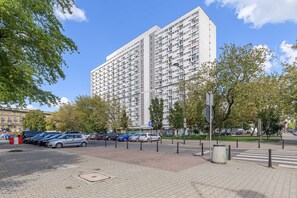 Een meerlaags woongebouw met een parkeerplaats ervoor.
