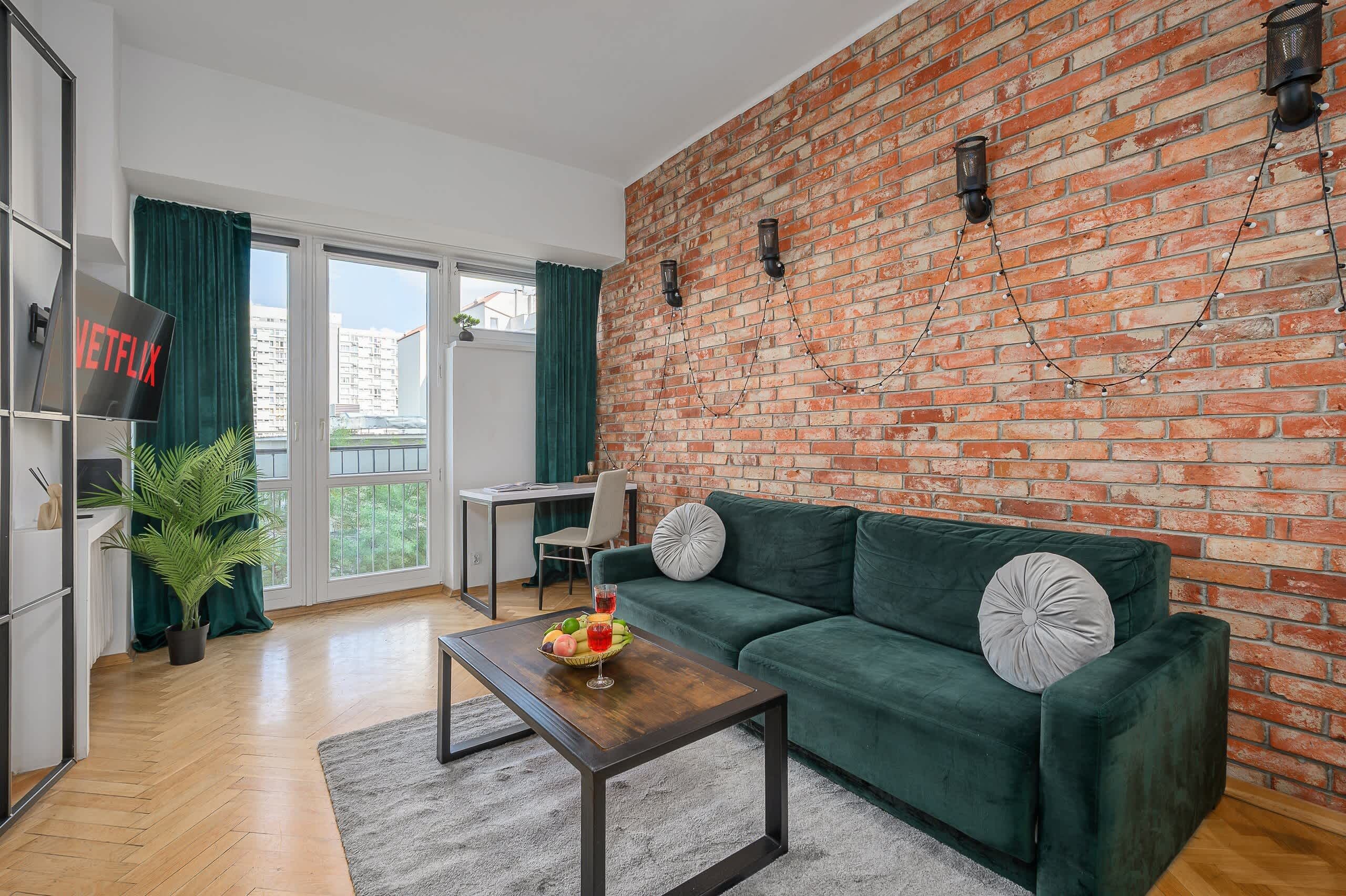 Una sala de estar moderna con un sofá verde, una mesa de centro, un televisor y una pared de ladrillo.