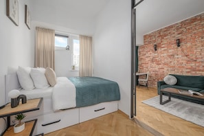 Ein modernes Schlafzimmer mit Bett, Nachttisch und Blick auf eine Ziegelwand.