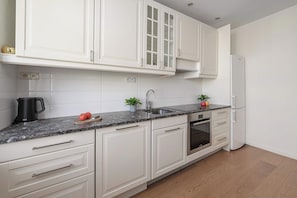 A modern kitchen with white cabinetry, a built-in oven, and a stainless steel sink. - Lumina 2-room Apart w/ Balcony Center & City View (Warszawa)