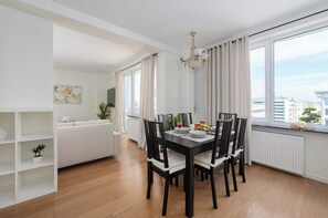 A modern dining area with a black table and chairs, a chandelier, and large windows with curtains. - Lumina 2-room Apart w/ Balcony Center & City View (Warszawa)