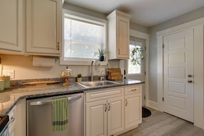 A kitchen with white cabinets, a granite countertop, a sink, and a window with blinds. - 'Olive & Oak' Mid-Century Sedalia Home w/ Patio (Sedalia)