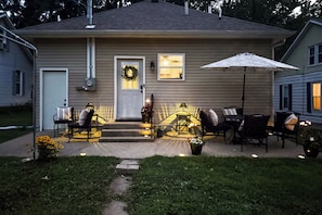A residential house with a front porch, outdoor seating area, and a decorative wreath on the door. - 'Olive & Oak' Mid-Century Sedalia Home w/ Patio (Sedalia)