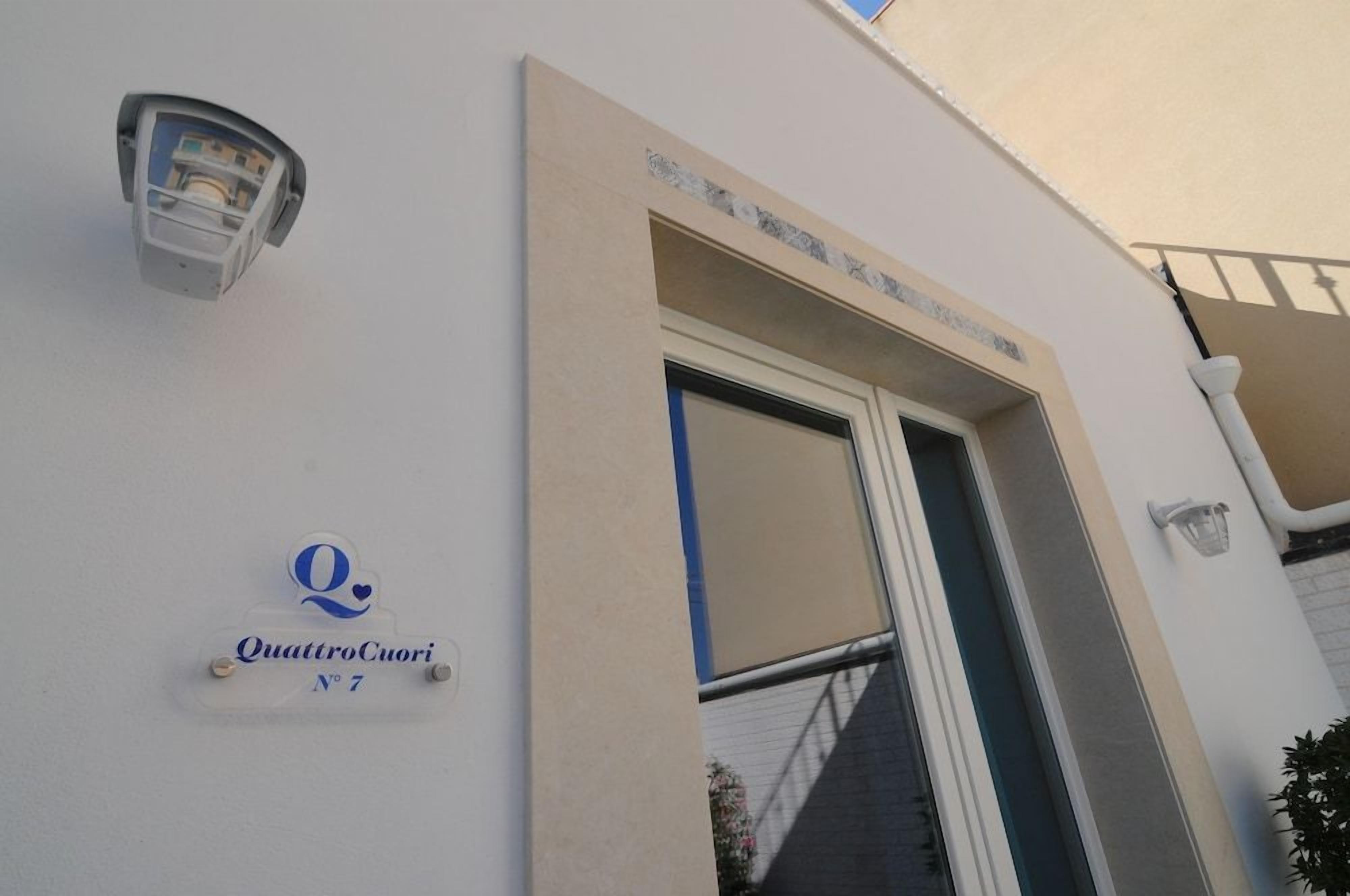 A building entrance with a sign reading 'QuattroCuori N°7' and a light fixture above it.