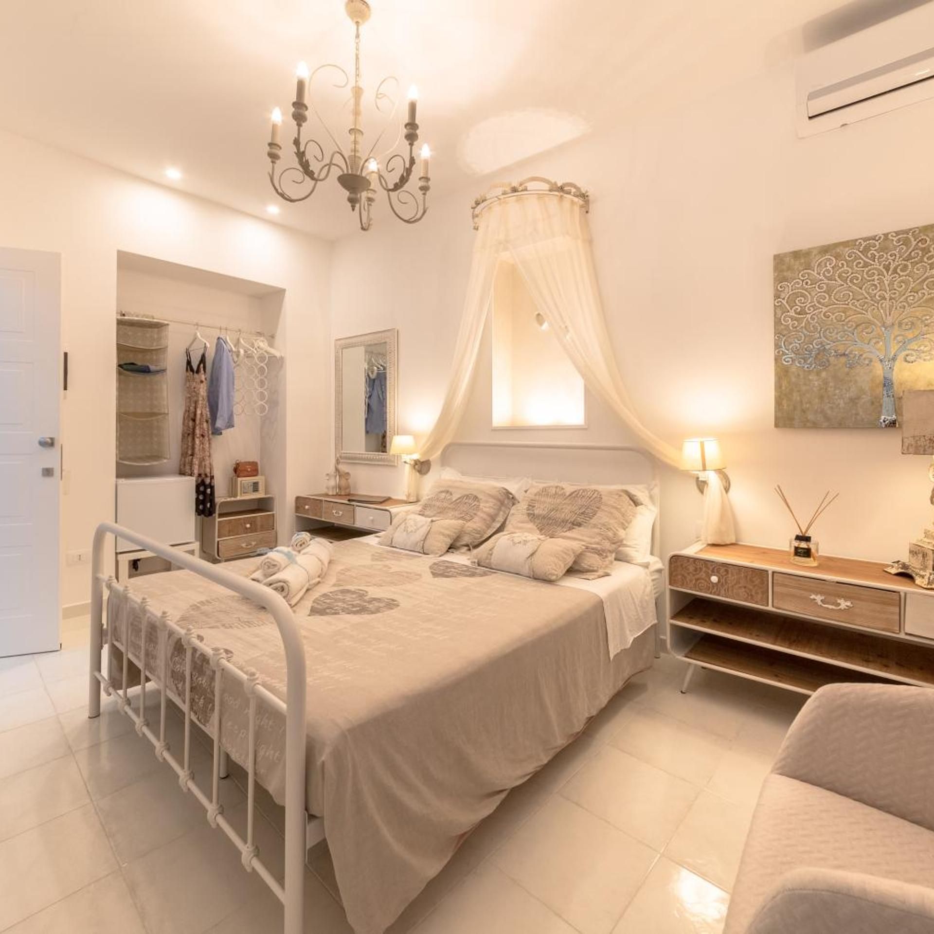 A bedroom with a bed, bedside tables, a wardrobe, and a chandelier.