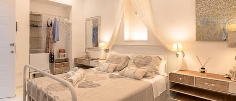 Un dormitorio con cama, mesitas de noche, armario y candelabro.