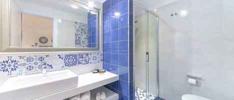 Un baño moderno con tocador blanco, un espejo grande y azulejos azules.