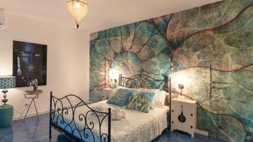 A bedroom with a bed, a wall mural, a hanging light fixture, and a nightstand.