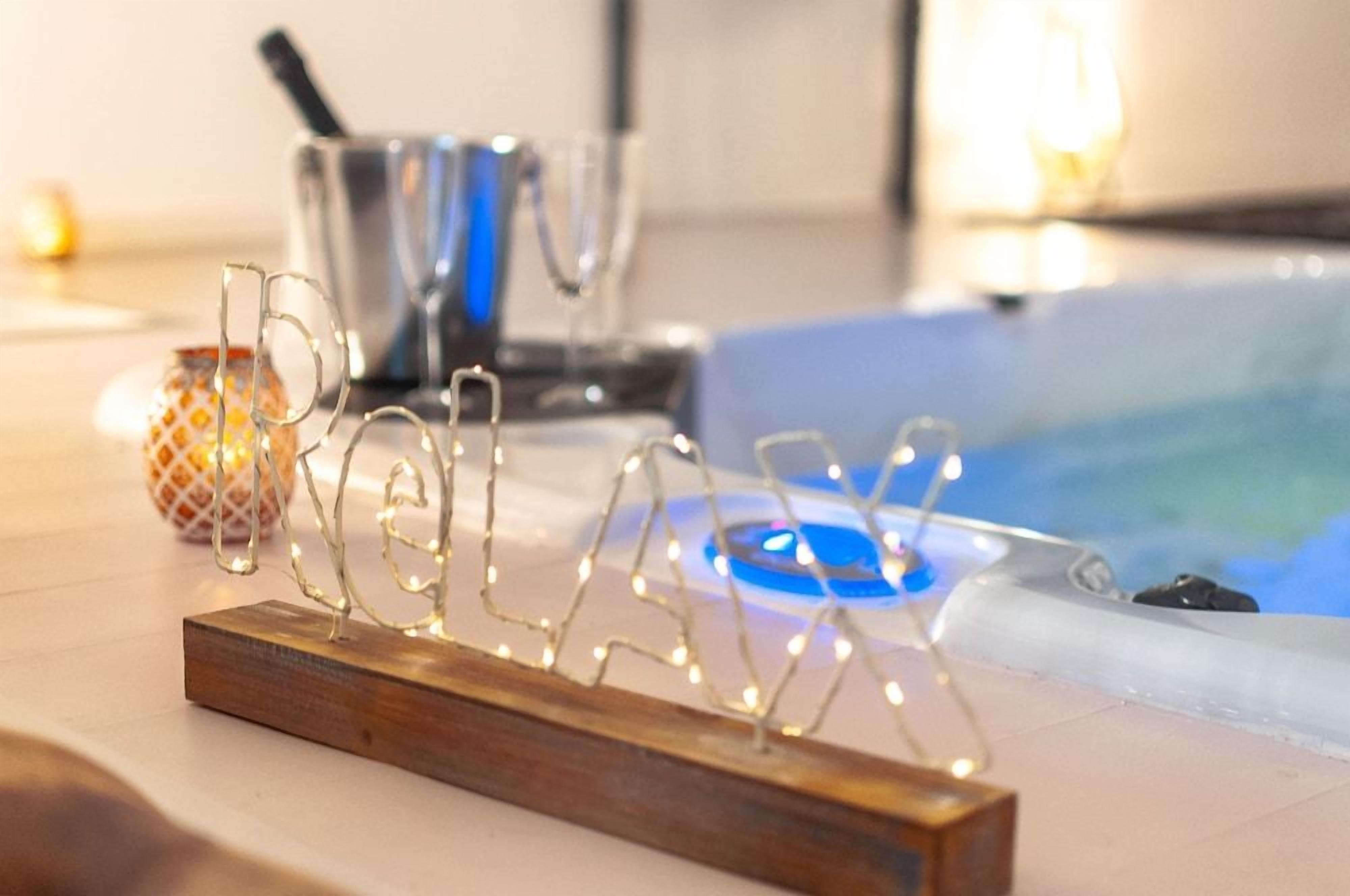 A wooden stand with a wireframe design, possibly a decorative piece, in a room with a bathtub and a metal container in the background.