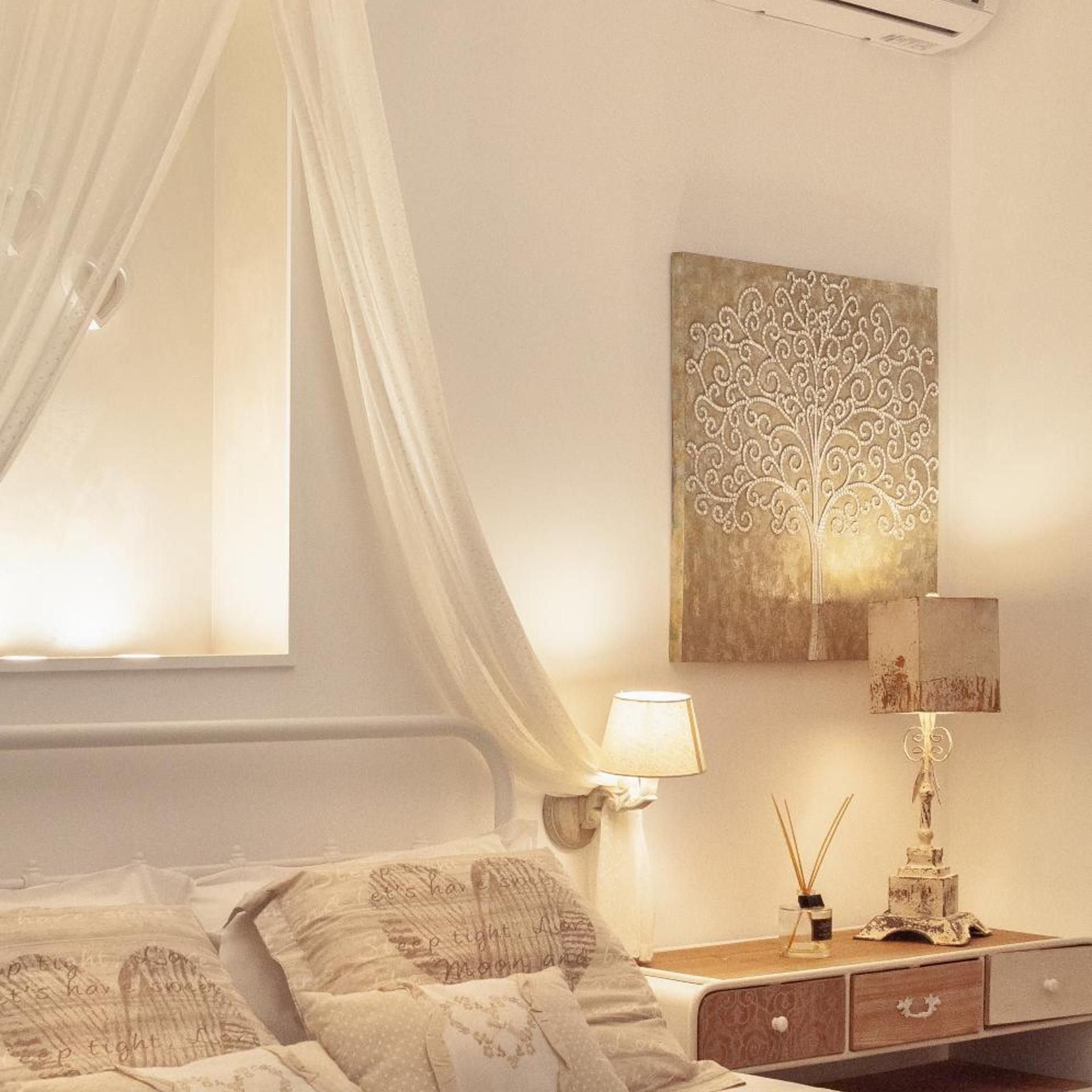 A bedroom with a bed, a nightstand, a lamp, and a wall art piece.