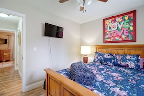 A bedroom with a wooden bed, a television mounted on the wall, and a painting with the words 'LOVE LOVE' on the wall. - Cozy Condo 6 Mi to Downtown Reno! (Reno)