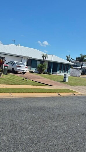 A residential property with a white house, a driveway, and a parked car.