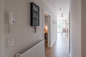Ein Flur mit weißem Heizkörper, fest installiertem Telefon und Kleiderhaken.