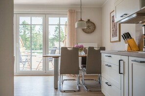 A modern kitchen with a dining area, large windows, and a view of the outdoors. - Holiday apartment with 1 bedroom (Prerow)
