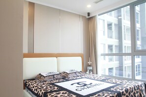 Habitación de hotel con un ventanal grande, una cama con cubrecama de temática Chanel y vistas a un edificio.