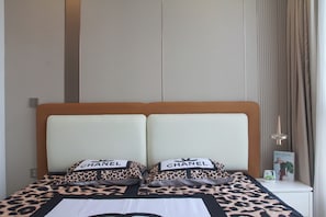 Habitación de hotel con una cama con cubrecama estampado de leopardo y dos almohadas con la marca 'CHANEL'.