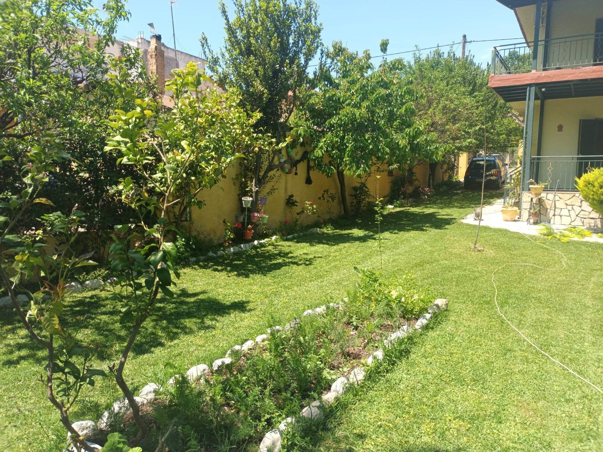 Ein gepflegter Garten mit Rasen, einer Steinmauer und verschiedenen Pflanzen.
