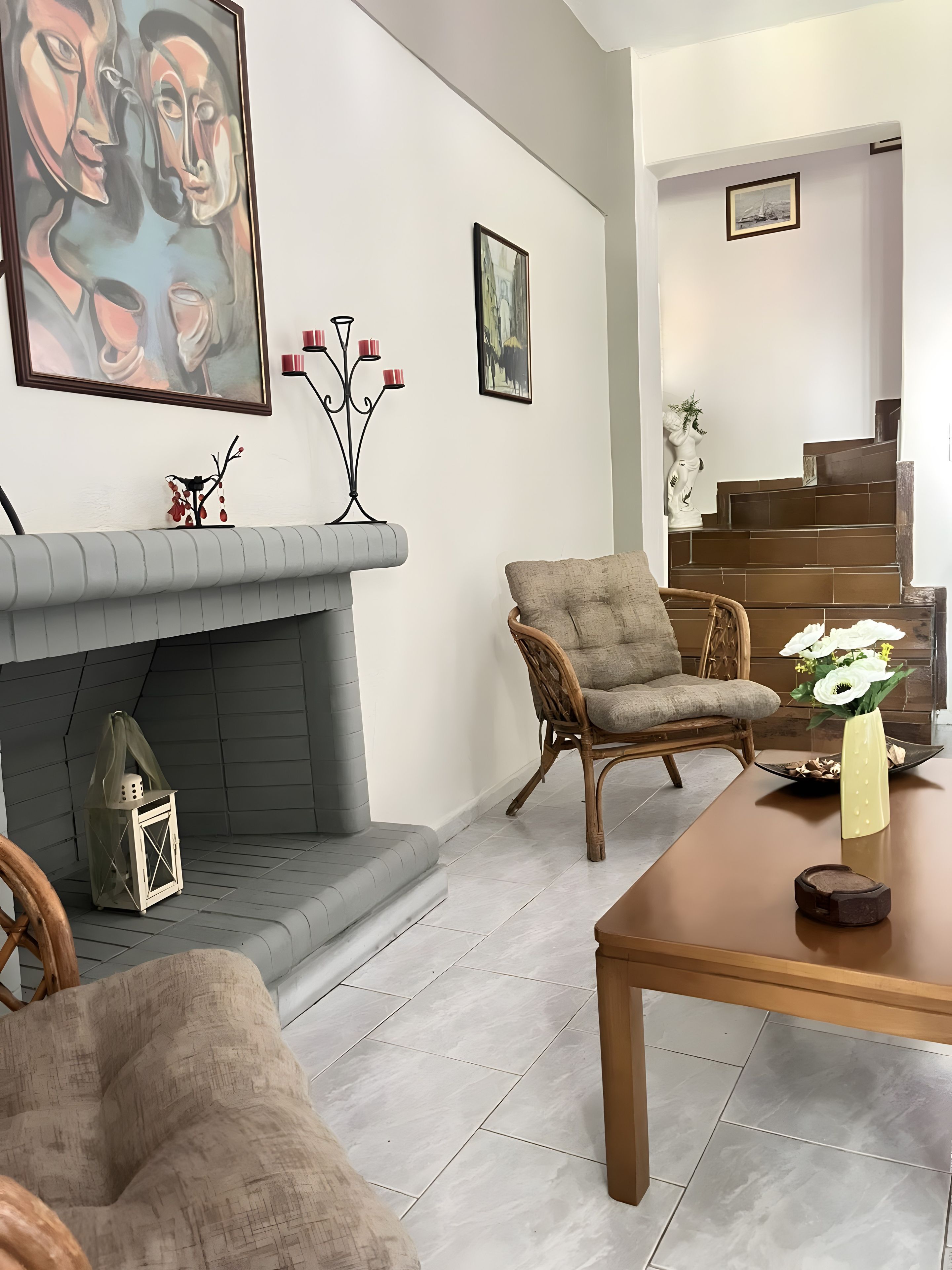 Un salon avec une cheminée, un canapé, un fauteuil, une table et un escalier.
