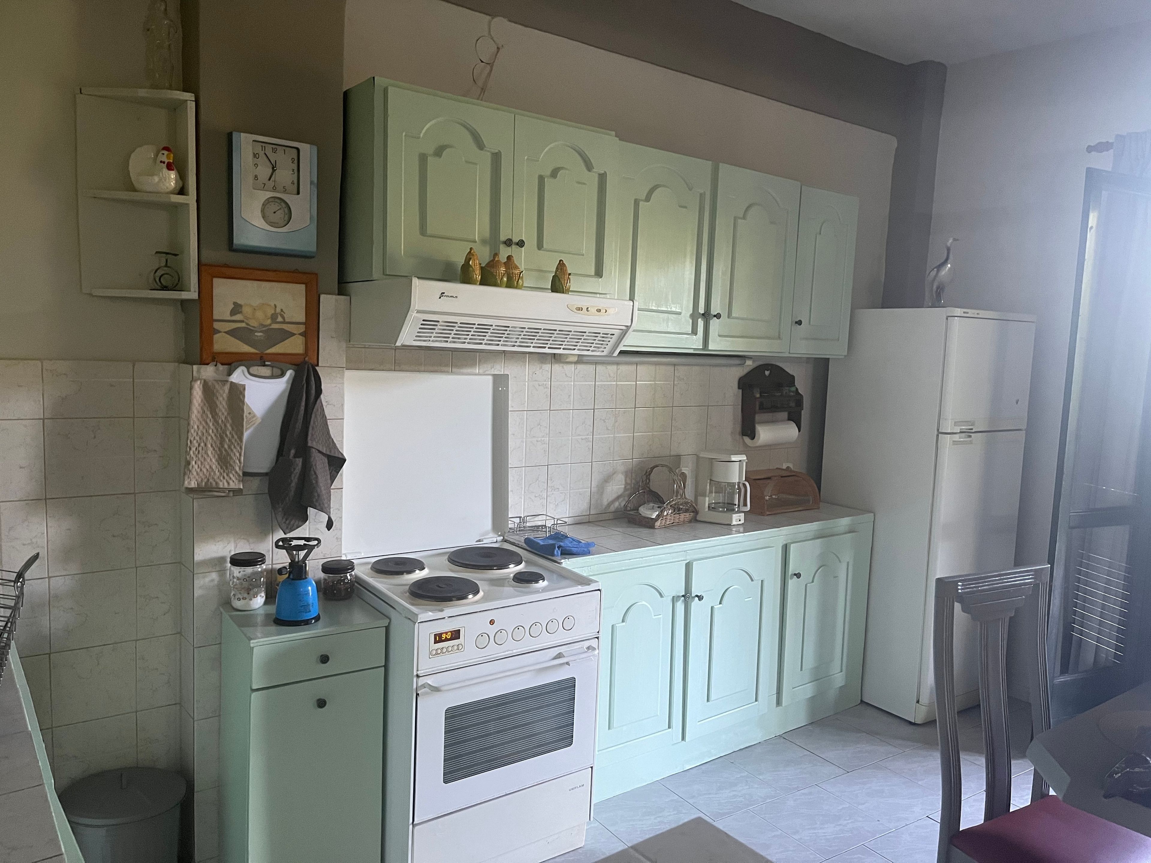 A compact kitchen with a stove, a refrigerator, and a coffee maker.
