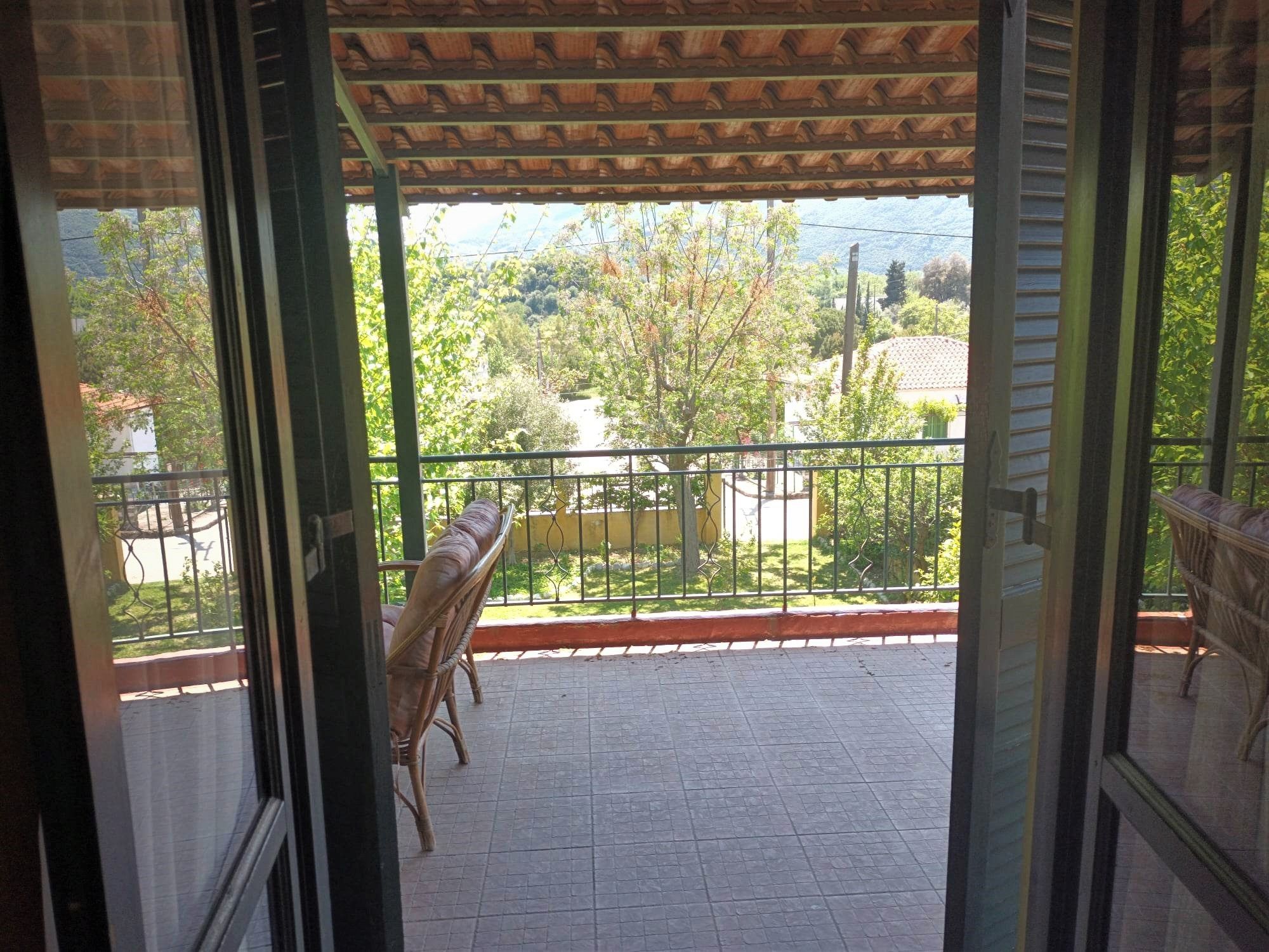 Un balcon donnant sur un paysage verdoyant et sur un bâtiment situé au loin.