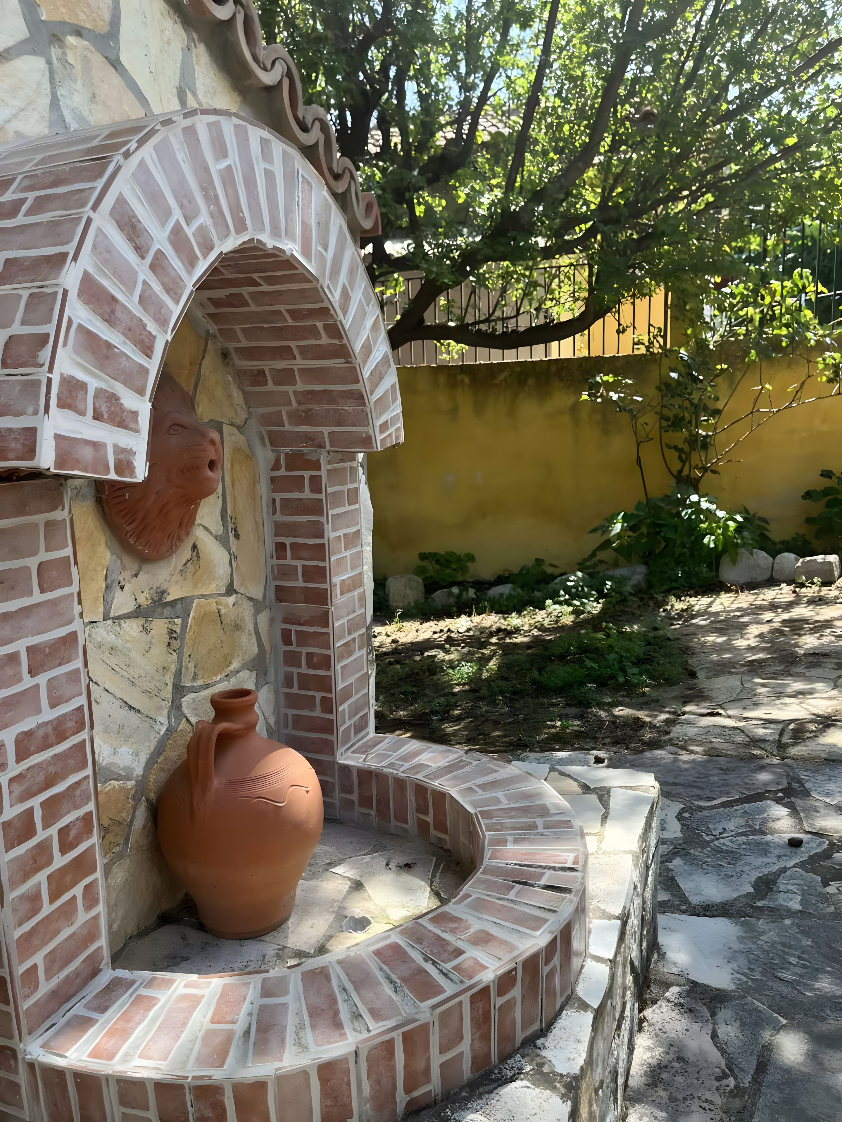 Une structure en briques contenant un pot en terre cuite à l’intérieur.